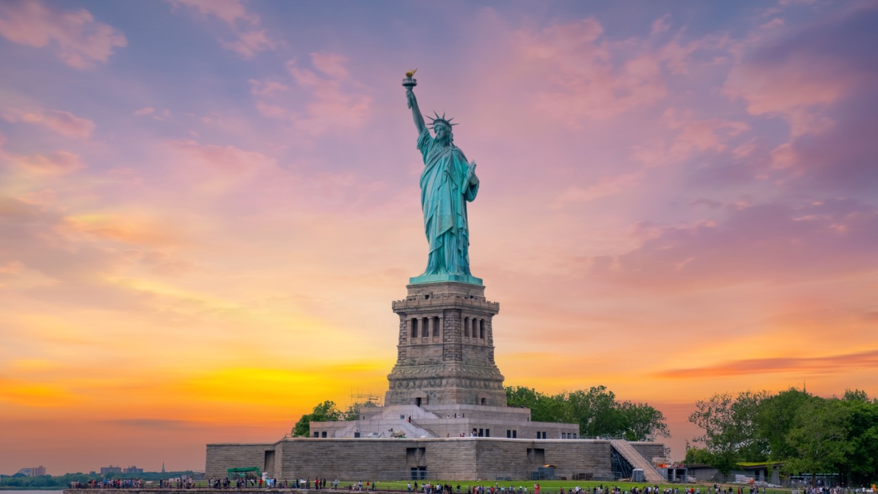 Statue of Liberty at sunset and Manhattan skyline, New York City.